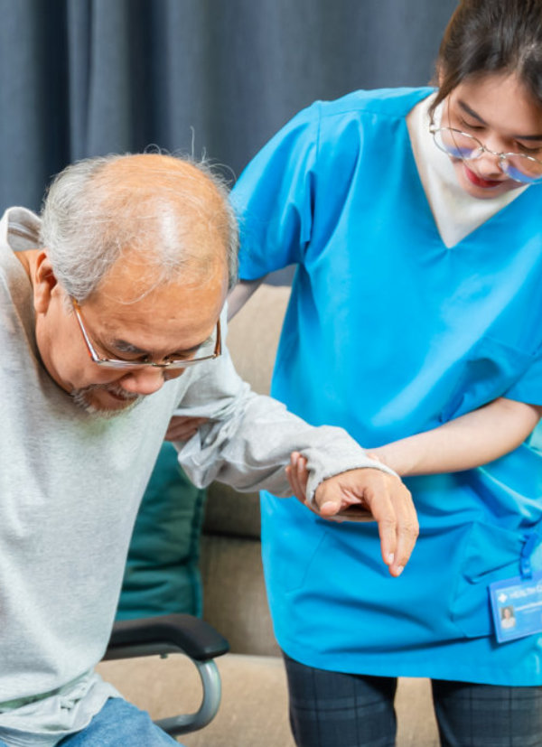 caregiver is helping the senior man to stand up