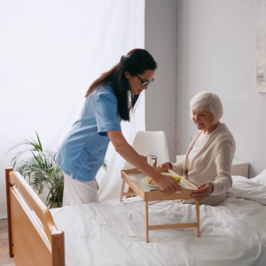 caregiver give food to the senior woman