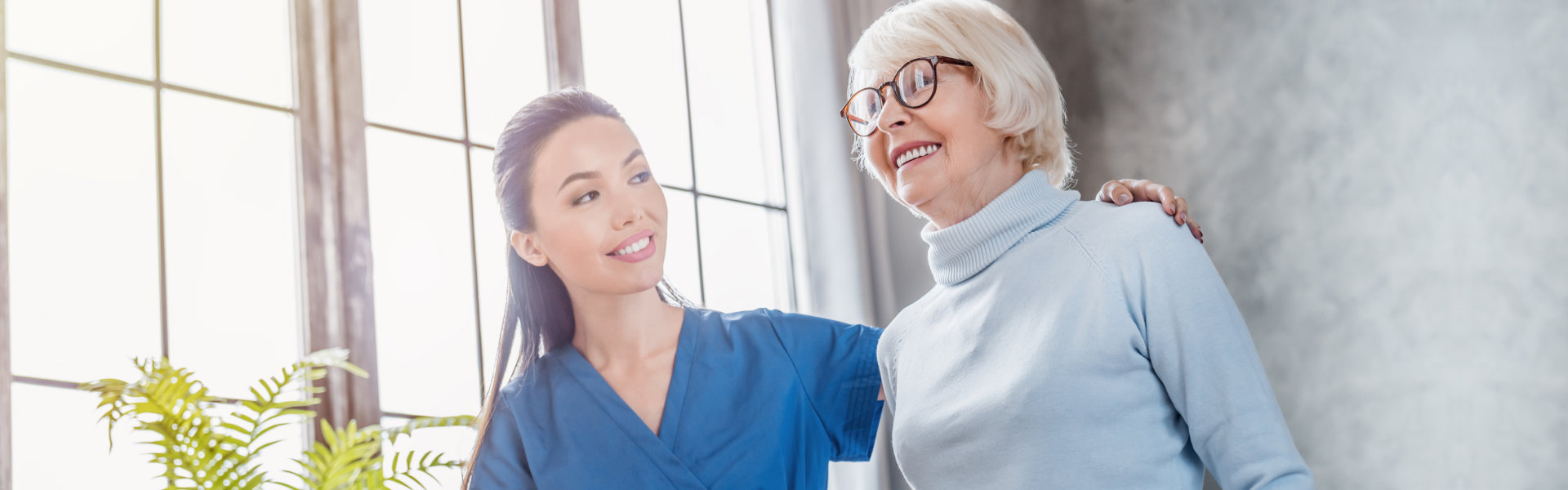 nurse helping senior woman to walk with walker at home